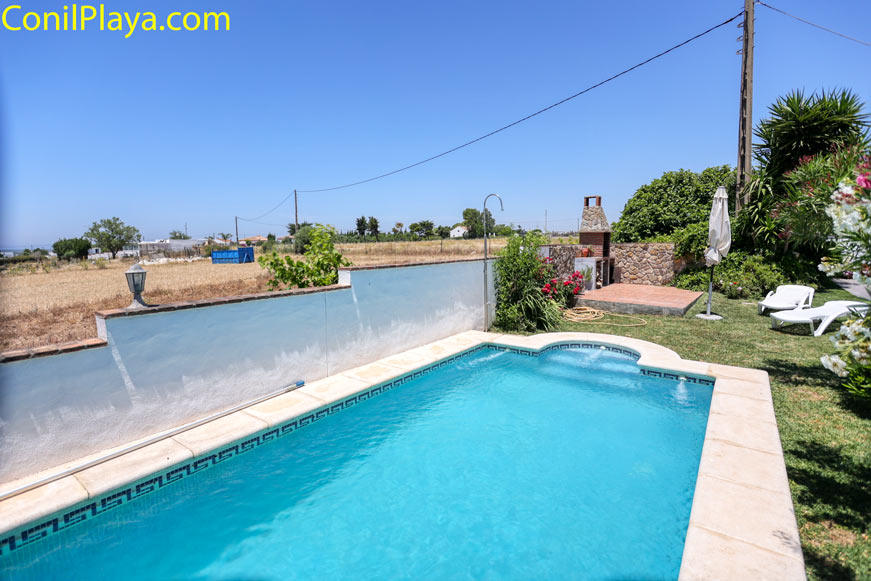Piscina privada junto a zona de barbacoa y jardín con tumbonas