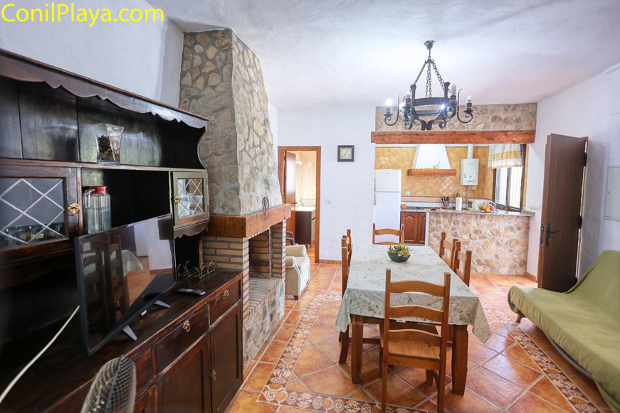 Comedor rustico con mesa grande y cocina al fondo visto desde la entrada