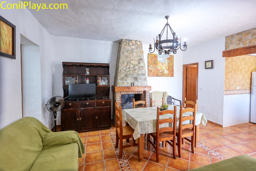 Salón rústico con chimenea, comedor y muebles de madera visto desde una esquina