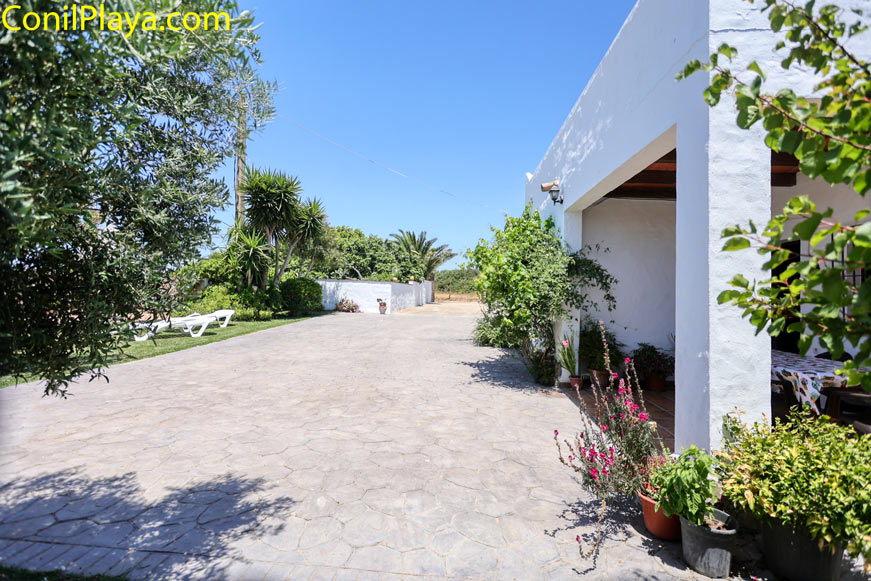 Aparcamiento de vivienda con plantas y zona de jardín junto a porche