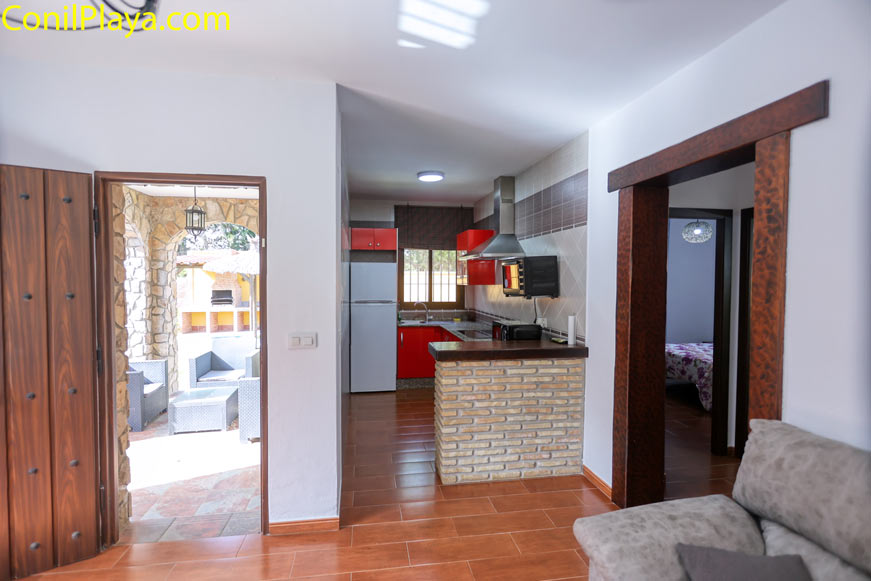 Cocina moderna con muebles rojos vista desde el salón y acceso exterior