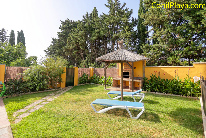 Jardín de césped con hamacas, sombrilla y barbacoa junto a seto privado