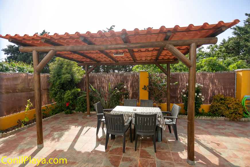 Porche con mesa y sillas bajo pérgola de madera junto a jardín privado