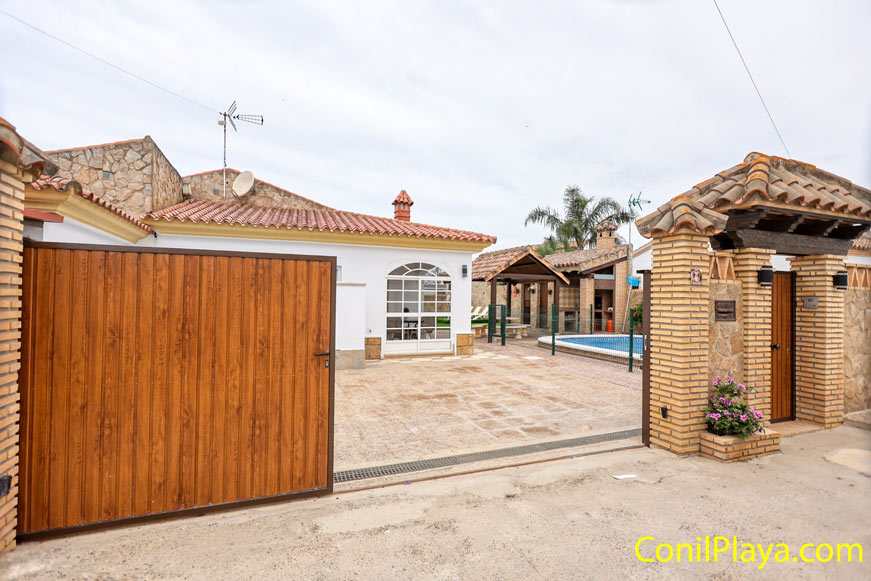 Entrada exterior con portón de madera y piscina junto a vivienda de una planta