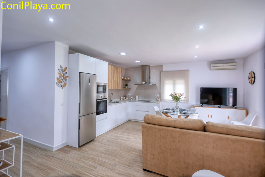 Salón moderno con cocina integrada, sofá beige y mesa de comedor redonda
