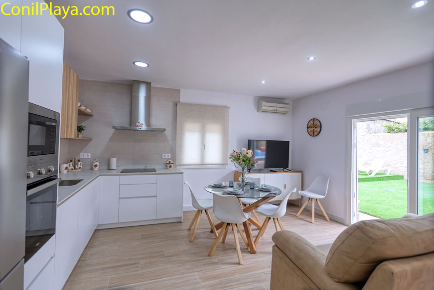 Comedor moderno con mesa redonda y cocina integrada visto desde el salón