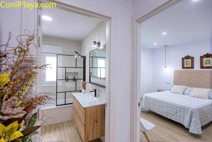 Cuarto de baño moderno junto a dormitorio con cama grande