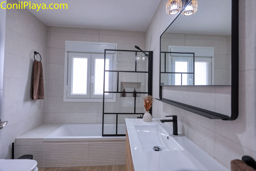 Cuarto de baño moderno con bañera y gran espejo rectangular