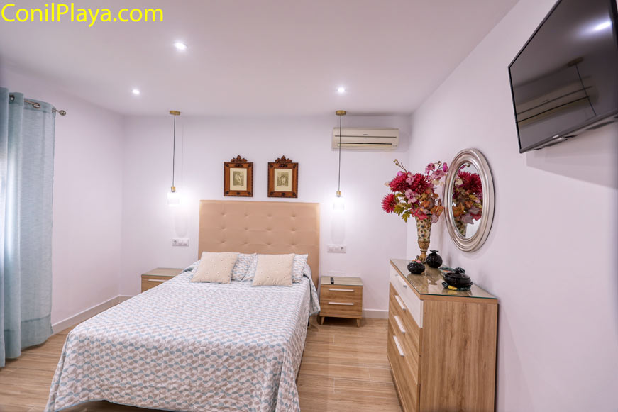 Dormitorio principal amplio con cama doble, cómoda, televisión y decoración moderna