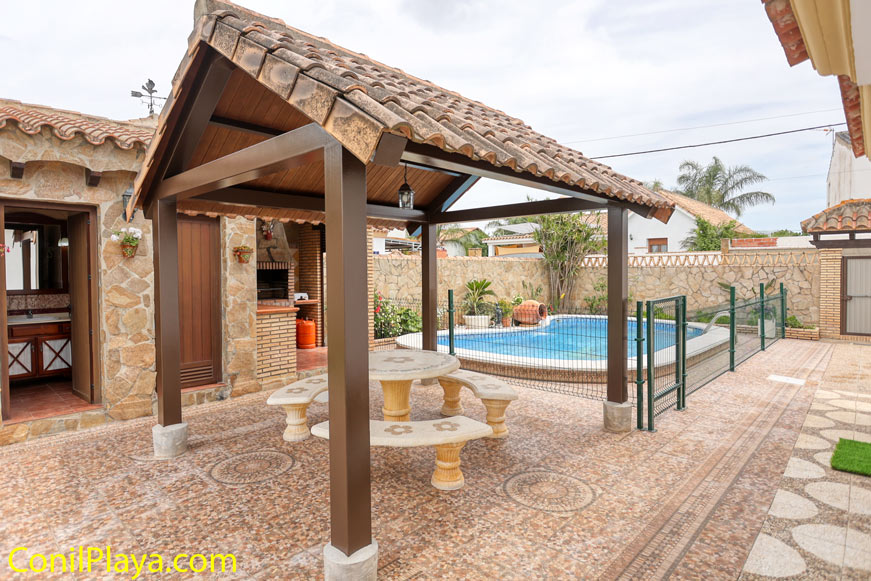 Merendero cubierto con mesa y piscina vallada en patio privado
