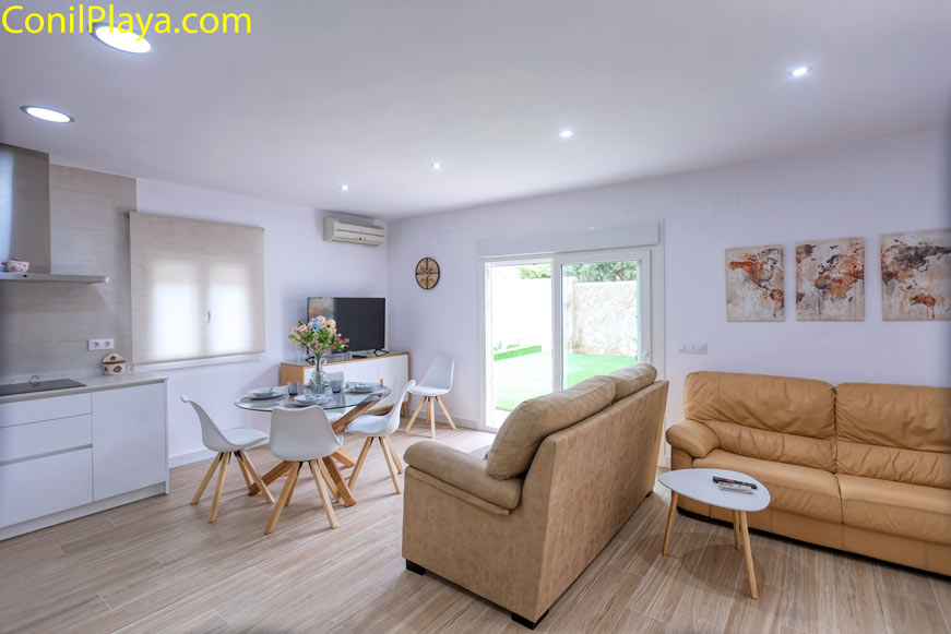 Vista del salón moderno con sofá beige mesa blanca y acceso al jardín
