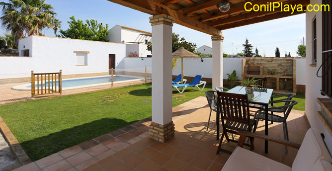 porche con mesa y sofá junto a la barbacoa y la piscina