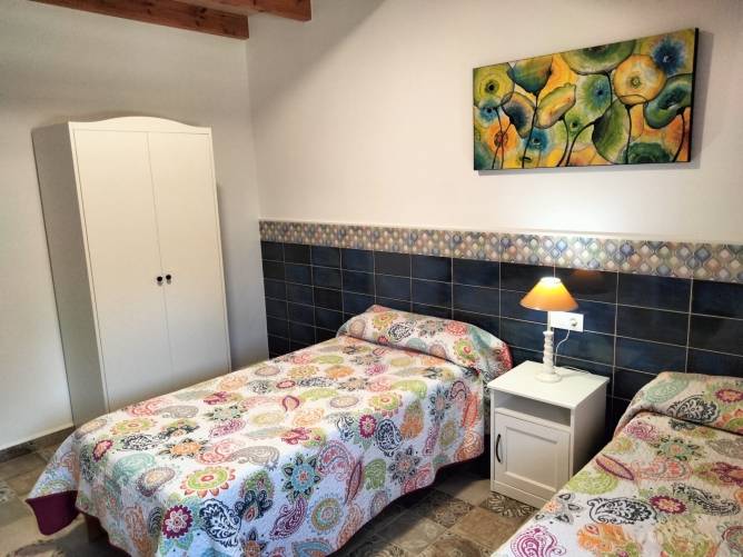 Dormitorio con dos camas individuales armario y lampara de noche encendida