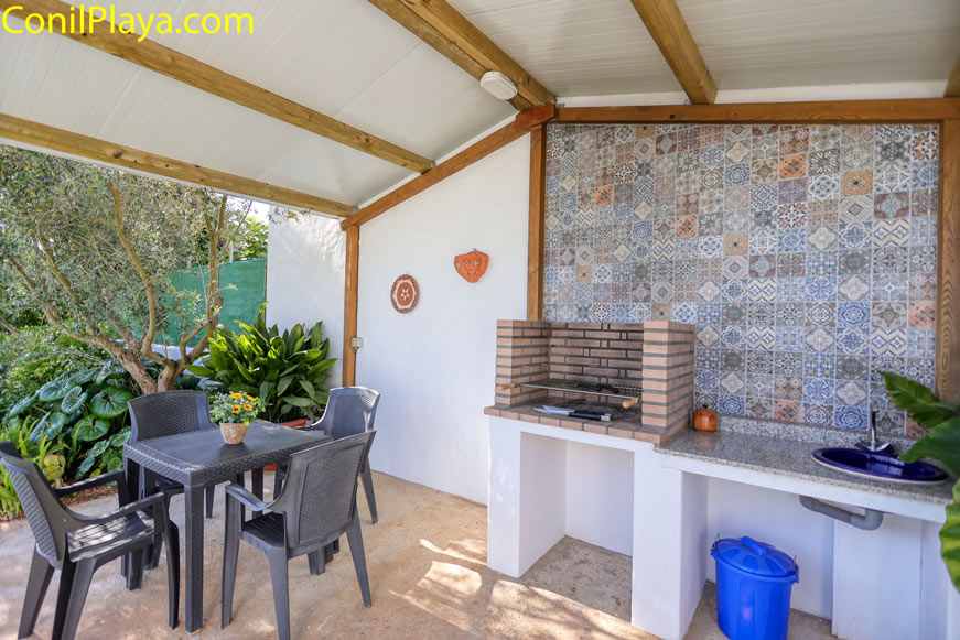 Porche cubierto con barbacoa mesa y fregadero junto a plantas decorativas