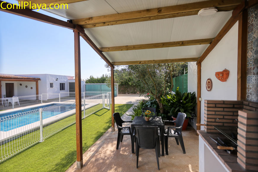 Porche cubierto con barbacoa mesa y sillas junto a piscina privada