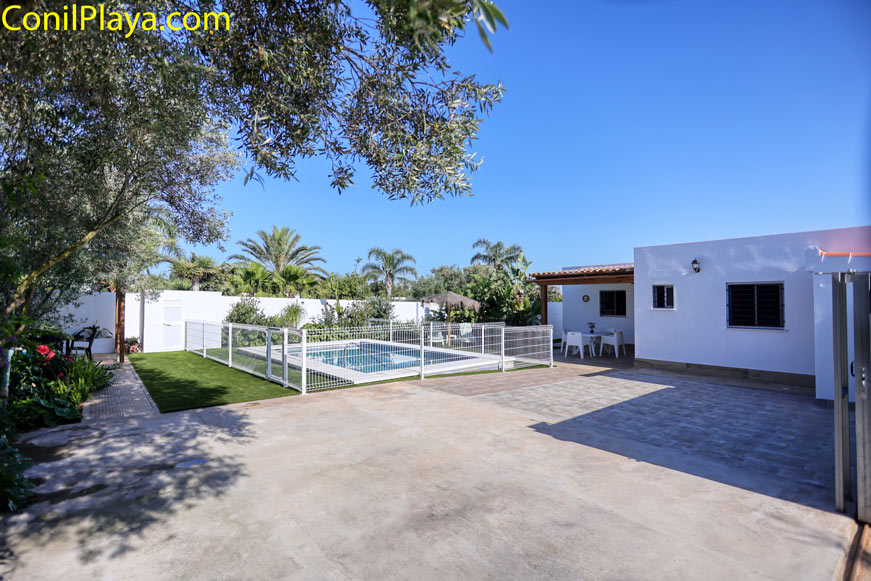 Zona exterior de la casa con piscina vallada y terraza junto al jardín