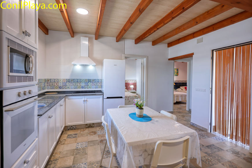 Cocina luminosa con mesa cubierta y sillas blancas desde la entrada