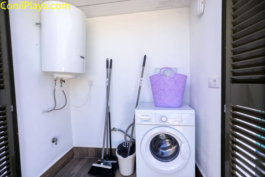 Lavadora y termo eléctrico junto a utensilios de limpieza desde el umbral