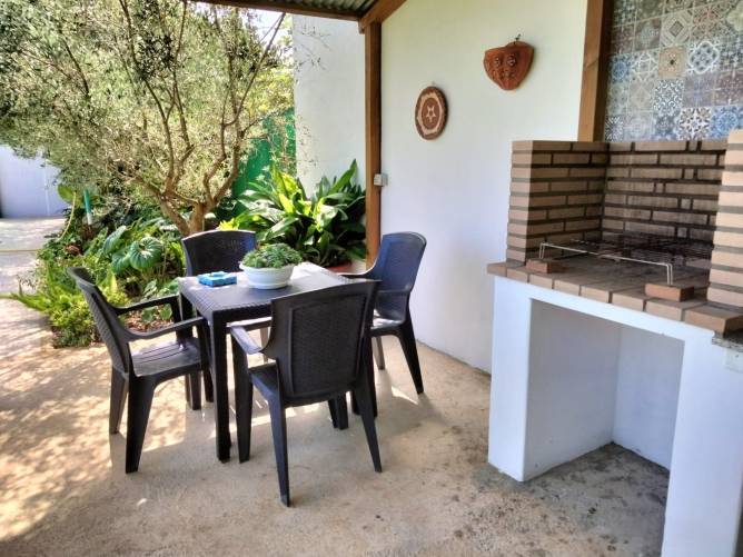 Porche con mesa y sillas de jardín junto a barbacoa de obra