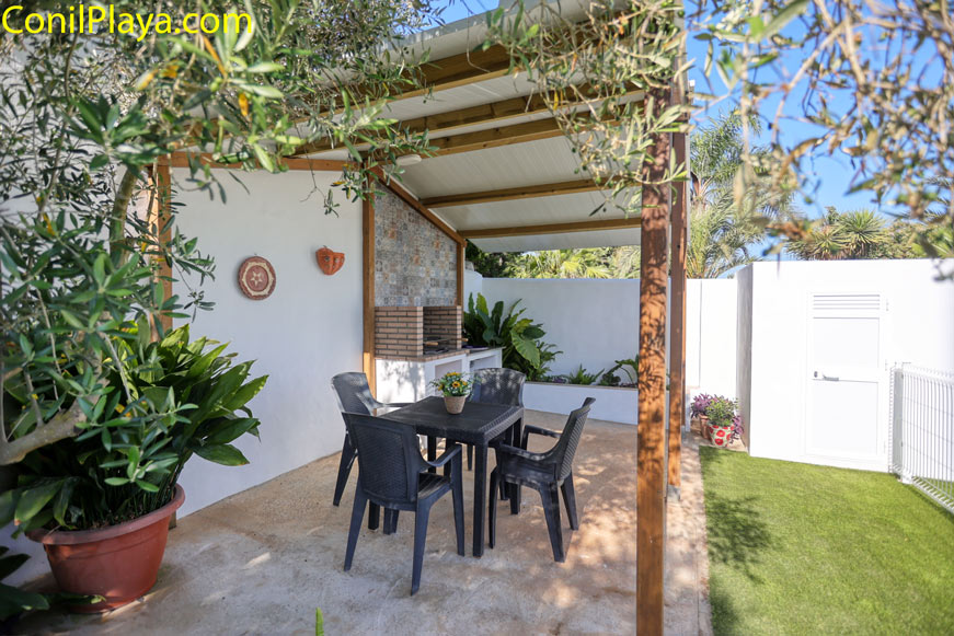 Porche con mesa y sillas junto a zona de barbacoa en jardín privado