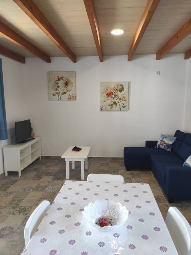 Salón con sofá azul mesa comedor y decoración floral en pared