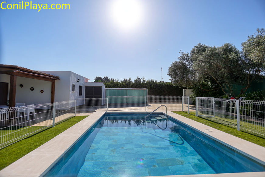 Piscina privada vallada junto a la casa y jardín con árboles y césped