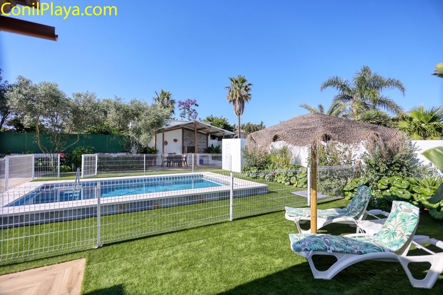 Piscina vallada con tumbonas y jardín junto a un alojamiento de vacaciones