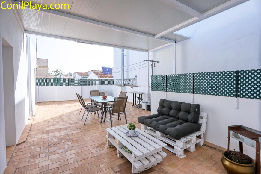 Terraza amplia con mesa sillas barbacoa y sofá vista desde zona cubierta