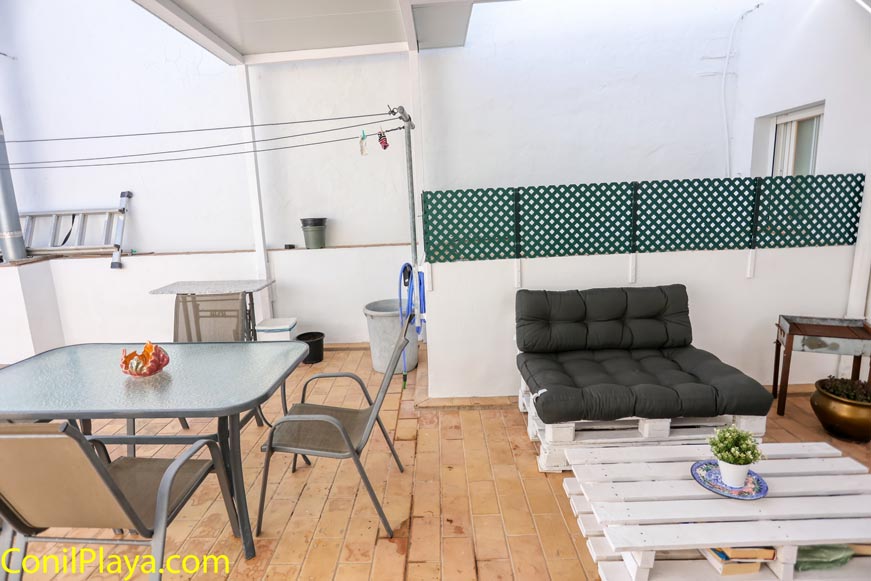Terraza con mesa de cristal y sofá de palets vista desde la entrada