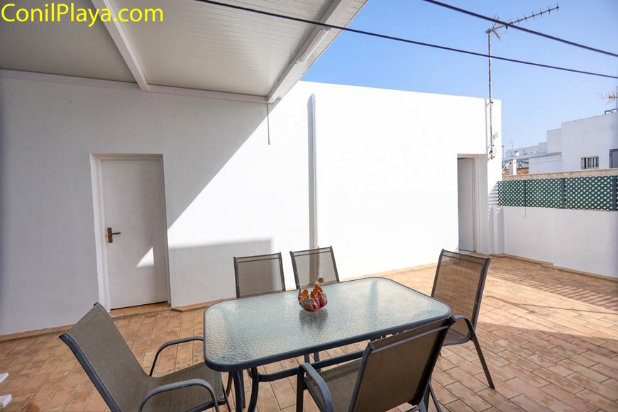 Terraza amplia con mesa de comedor y sillas junto a pared blanca