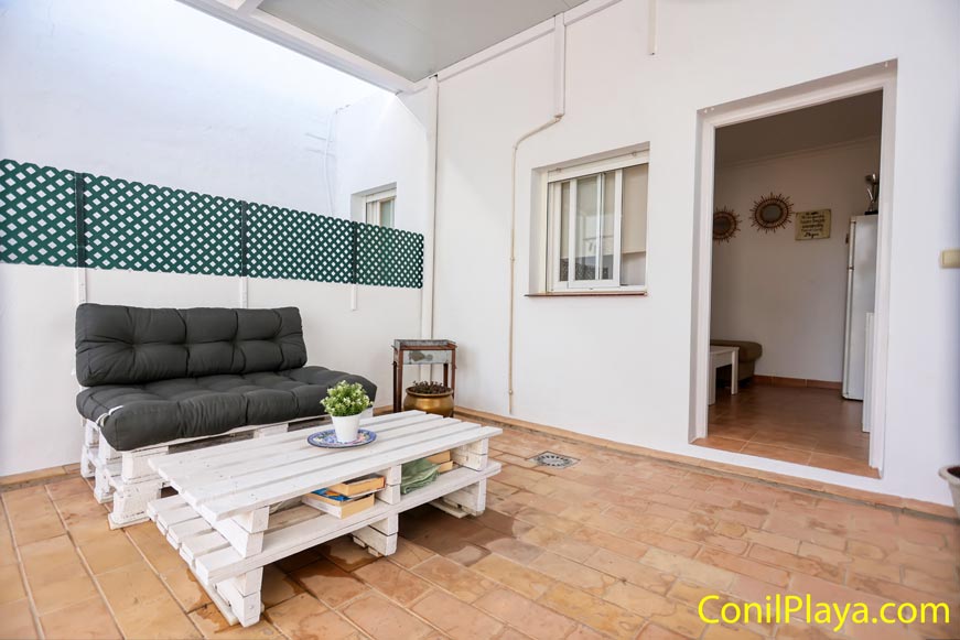 Porche con sofá chill out de palets y mesa blanca desde entrada