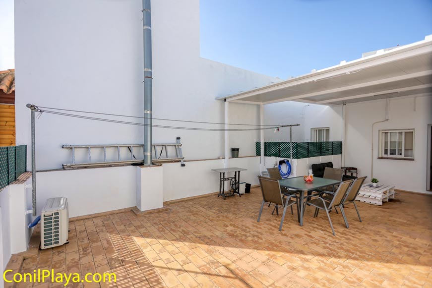 Amplia terraza con mesa, sillas y zona cubierta junto a vivienda