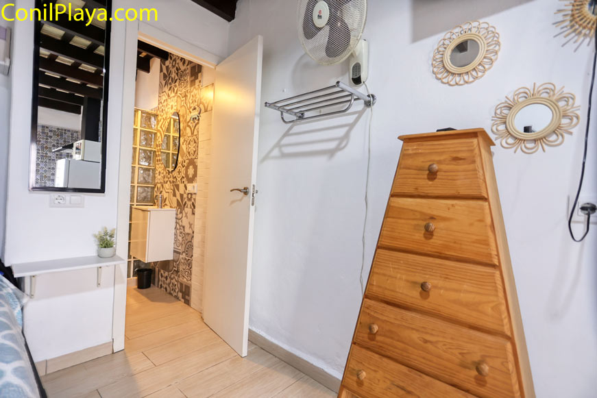 Dormitorio con sinfonier de madera y puerta abierta hacia el baño