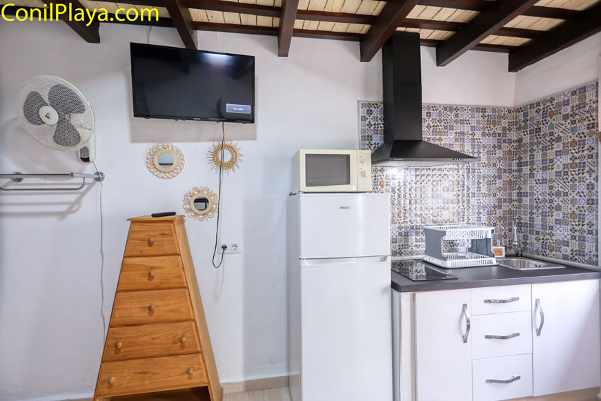 Cocina pequeña con nevera, microondas, televisor y fregadero moderno