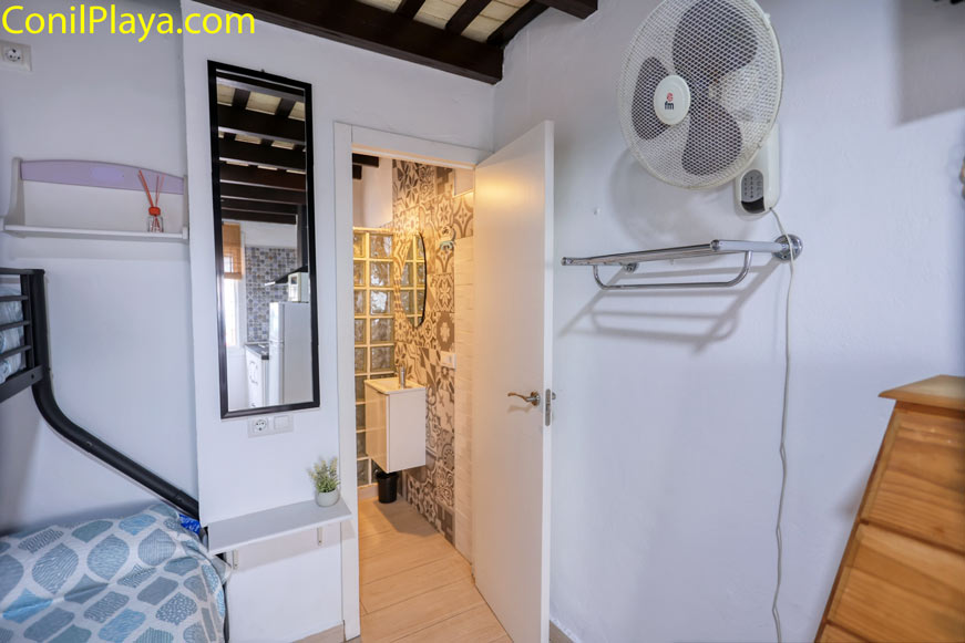 Vista de dormitorio con cama, ventilador y acceso al baño
