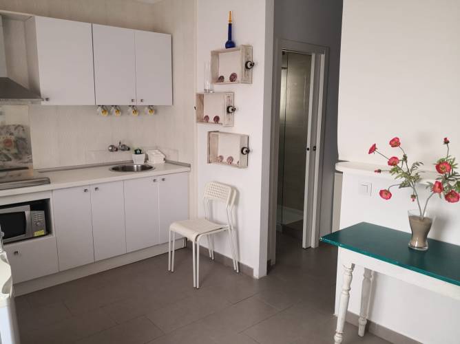Cocina moderna vista desde la entrada con muebles blancos y mesa pequeña