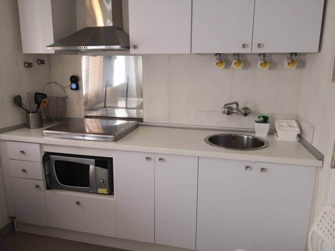 Cocina blanca moderna con microondas y vitrocerámica vista desde la entrada