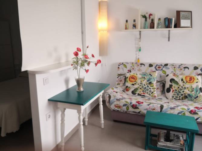 Salón con sofá colorido mesa auxiliar y estantería decorativa en primer plano