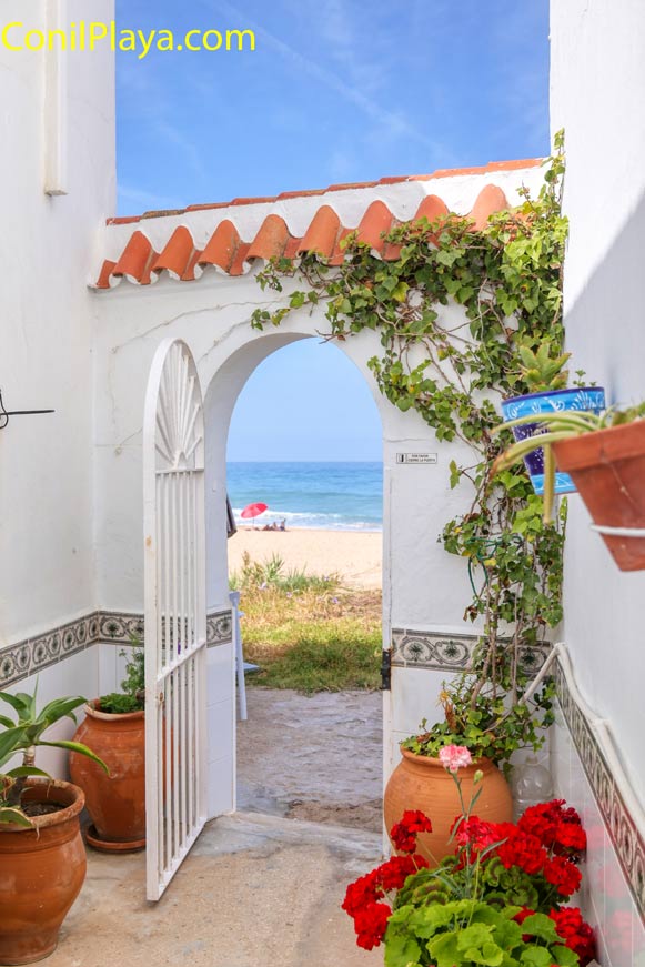 Entrada de patio andaluz con macetas y acceso directo a la playa