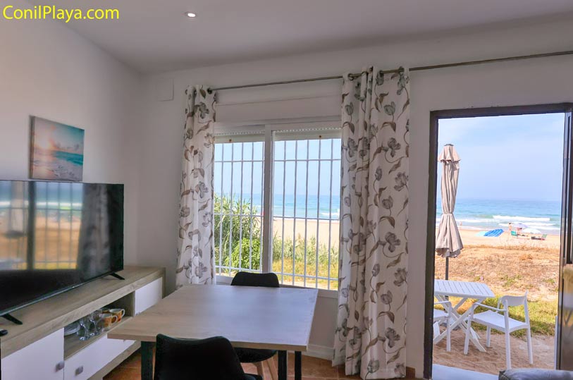 Comedor con mesa y televisión, vistas directas hacia la playa desde dentro