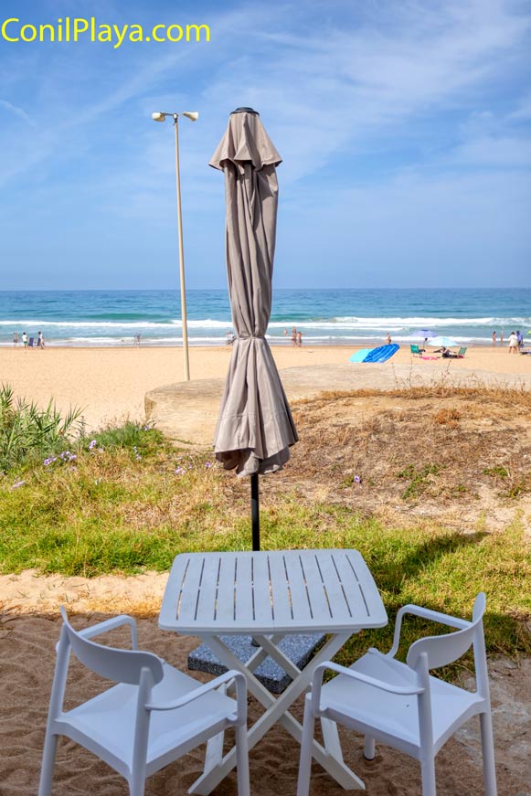Terraza con mesa y sillas blancas frente a la playa Fontanilla
