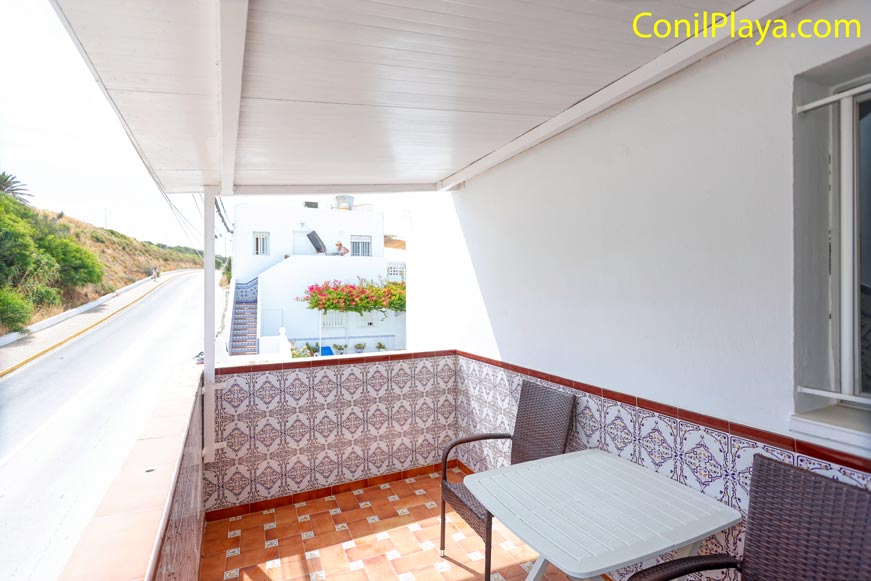 Terraza cubiera con mesa y sillas y vistas a la carretera de acceso a la fontanilla