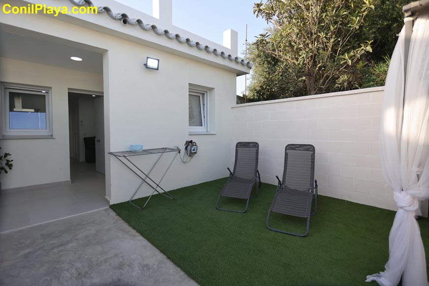 Jardín pequeño con dos tumbonas junto a la entrada de la casa patio