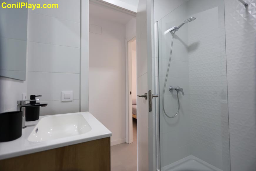 Cuarto de baño moderno con ducha y lavabo visto desde la entrada