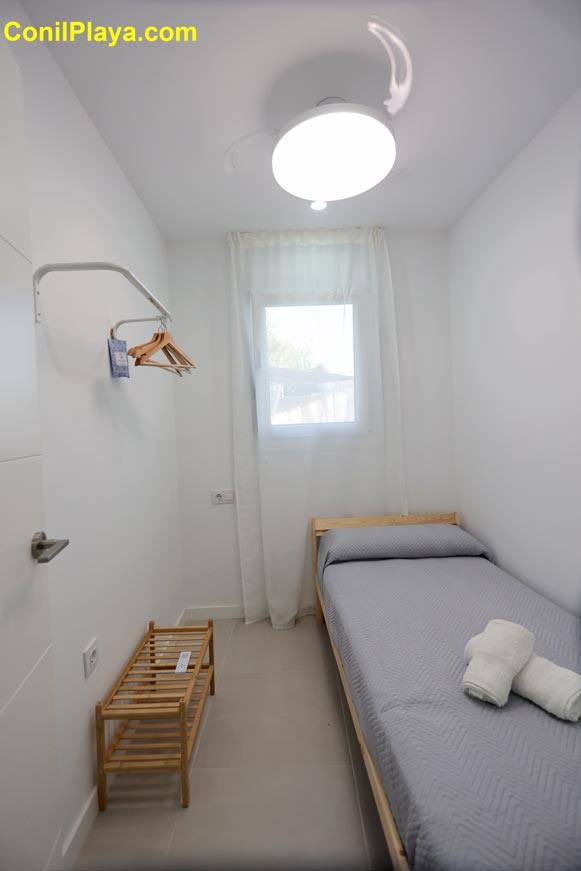 Dormitorio pequeño con cama individual junto a ventana y ventilador de techo
