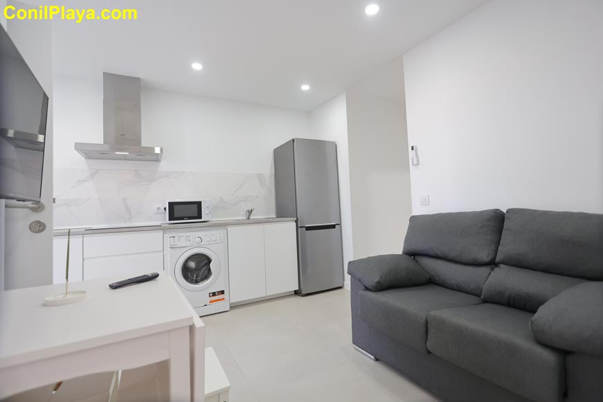 Cocina moderna abierta con sofá gris vista desde la entrada