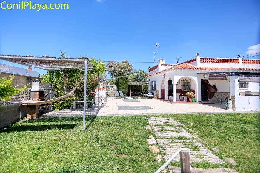 Jardín con césped barbacoa y terraza junto a la vivienda con porche