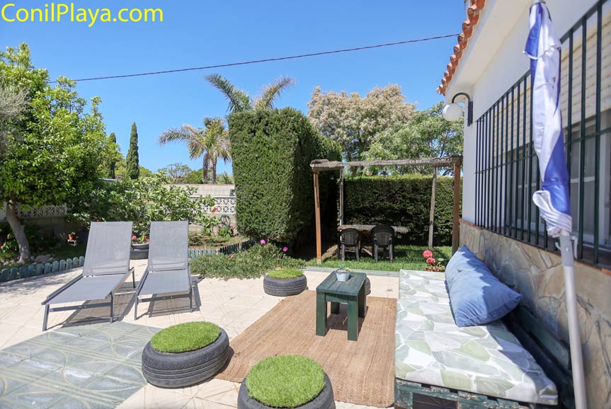 Zona de jardín con tumbonas, banco y mesa en espacio chill out privado