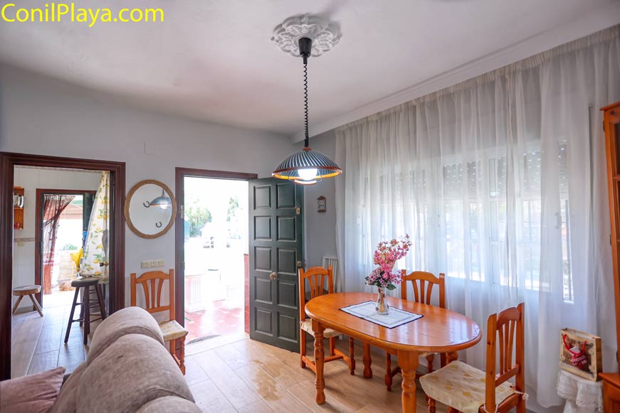 Comedor con mesa de madera y varias sillas vistas desde el salón
