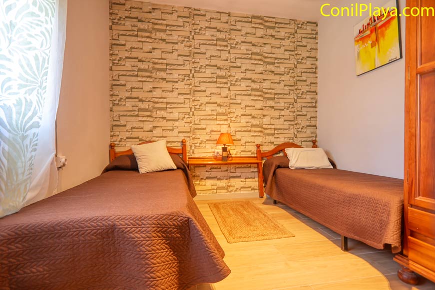Dormitorio con tres camas individuales, mesita central y decoración cálida